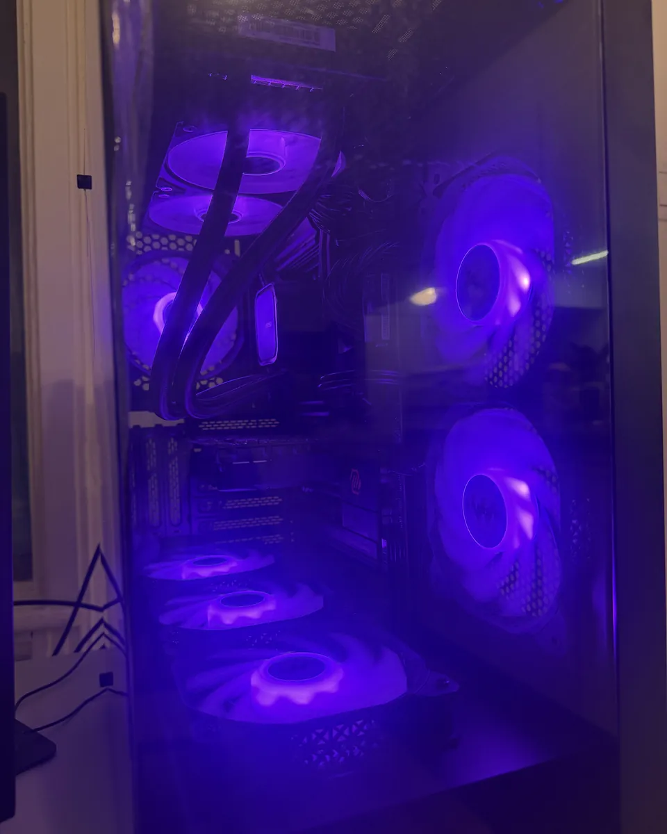 Inside of a black gaming PC with purple lighting and multiple RGB fans.