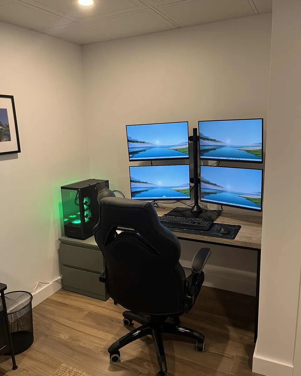 Trading workstation installed for a client with four displays on an articulated mount and a black tower with green lighting.