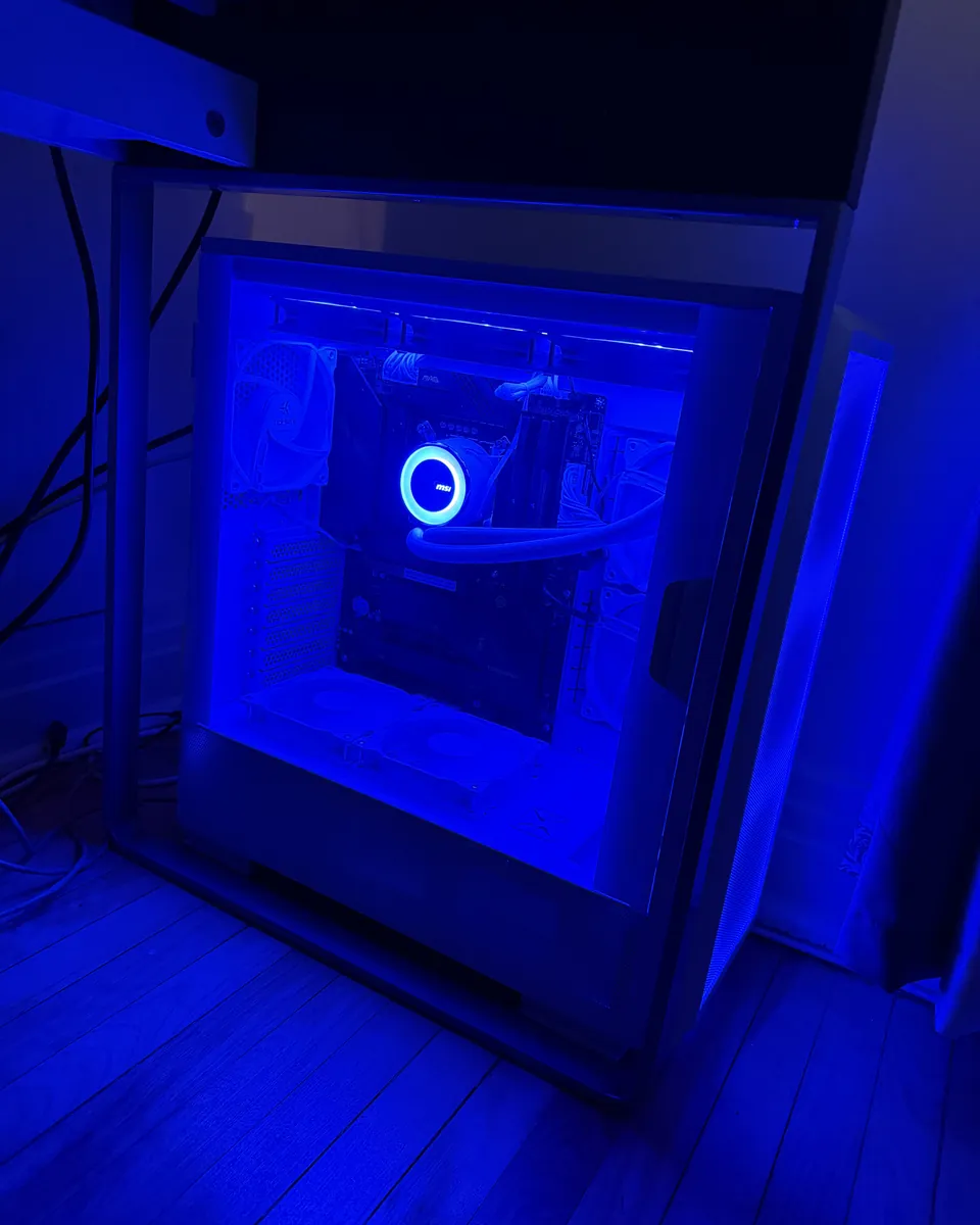 PC gaming blanc éclairé en bleu, avec refroidissement liquide et câblage interne visible.